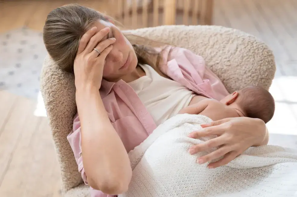 Mãe cansada amamentando o bebê em uma poltrona