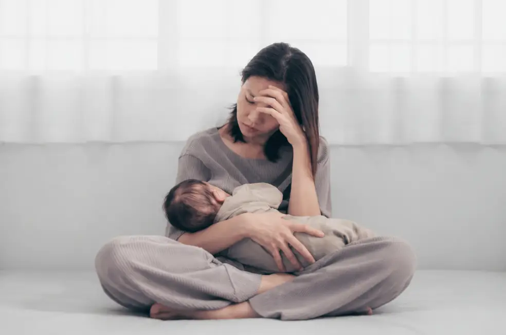 Mãe exausta segurando o bebê no colo